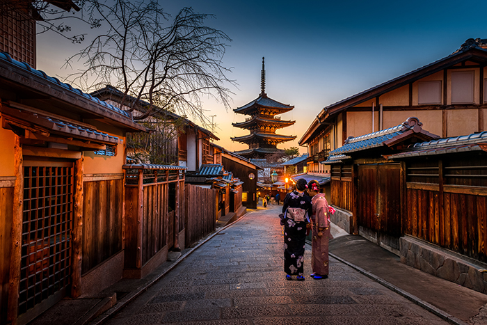 Un retrato de dos personas de pie junto a un impresionante templo en Kioto al atardecer - imágenes de Japón