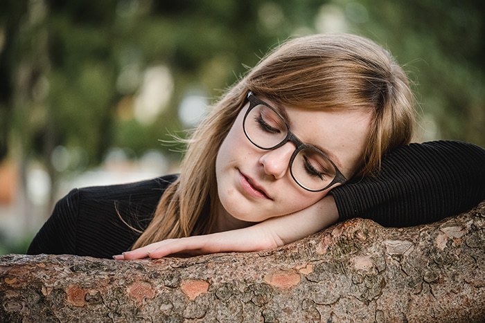 Retrato de una modelo femenina descansando sobre un árbol con un fondo natural retrato borroso