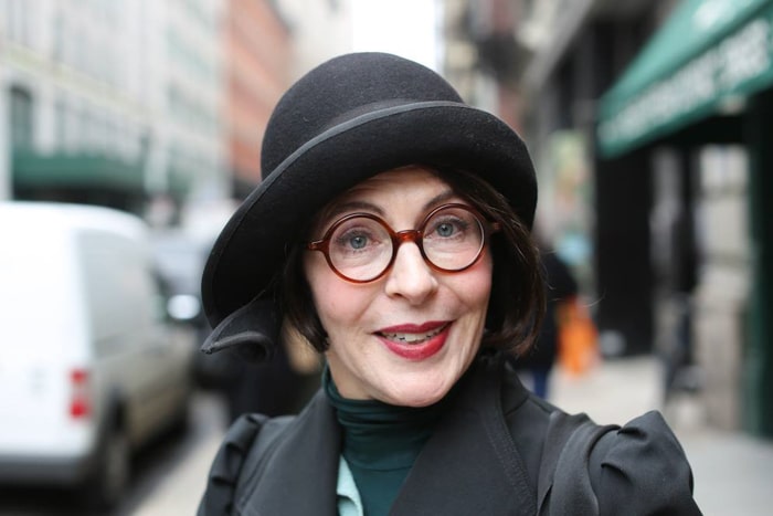 Un retrato de una mujer con sombrero negro y gafas rojas