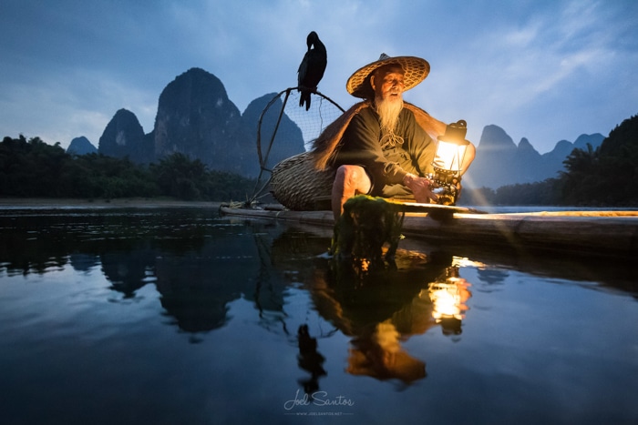 Un pescador asiático y un cormorán