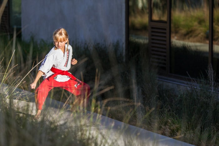 Un retrato de una niña en una pose de karate al aire libre