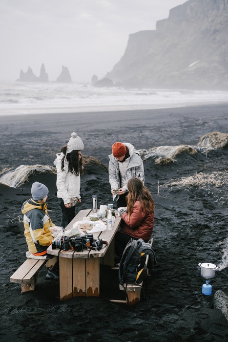 Una familia haciendo un picnic en una playa rocosa brumosa