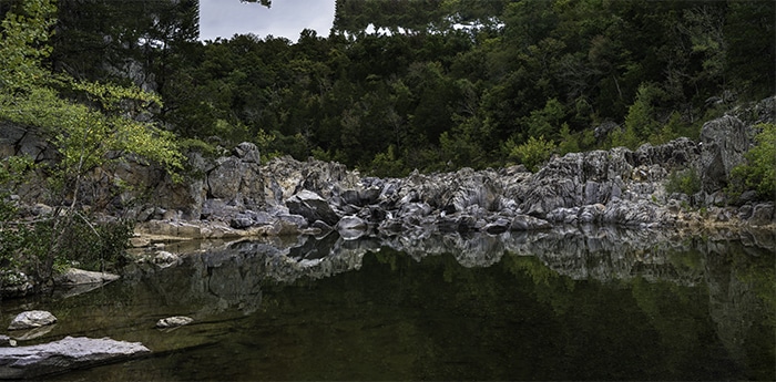 Panorama de 6 imágenes de un lago rocoso bajo los árboles