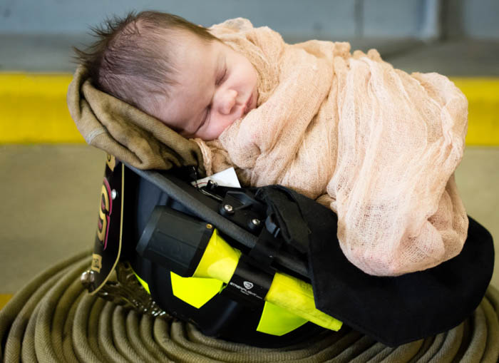 bebé recién nacido fotografiado en un casco de bombero.  poses de fotografía de recién nacido