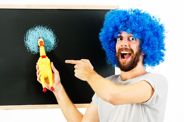 Hombre con peluca azul y pollo de goma.