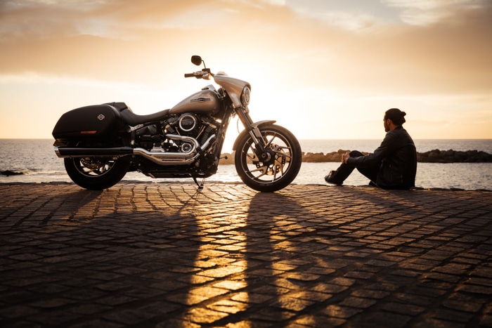 Foto de un hombre sentado en una playa con una moto
