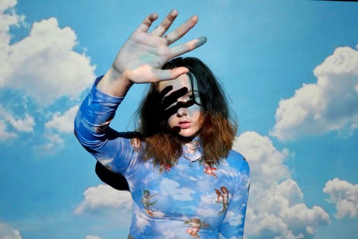 Un retrato de una modelo femenina con una foto proyectada de nubes sobre ella
