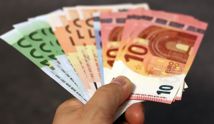 Una mano sosteniendo un abanico de billetes de euro