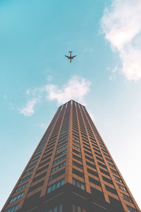 Foto de un avión y un edificio alto desde una perspectiva hacia arriba