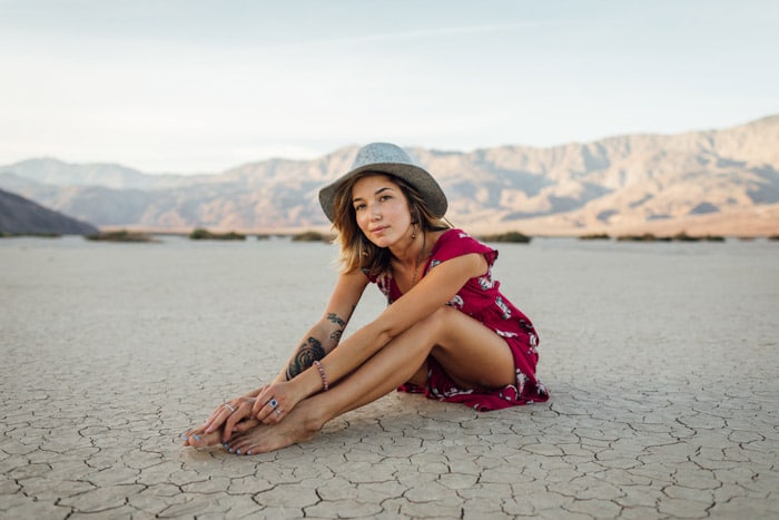 Brillante retrato de una niña sentada en un terreno desértico, posando personas en fotografías