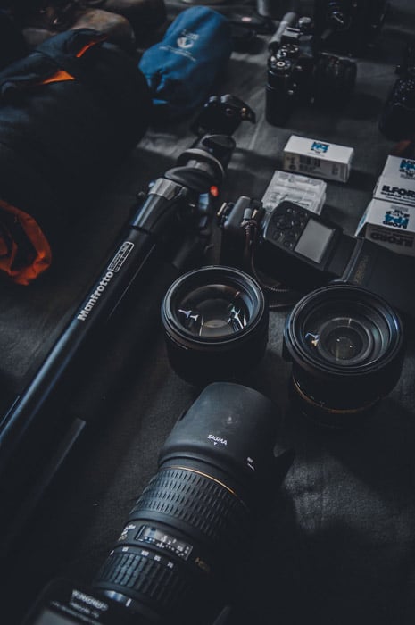 Lentes de cámara, trípode y otros equipos de fotografía de una mesa negra
