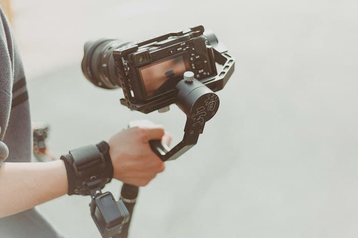 Una foto luminosa y aireada de un fotógrafo sosteniendo una cámara DSLR en un trípode