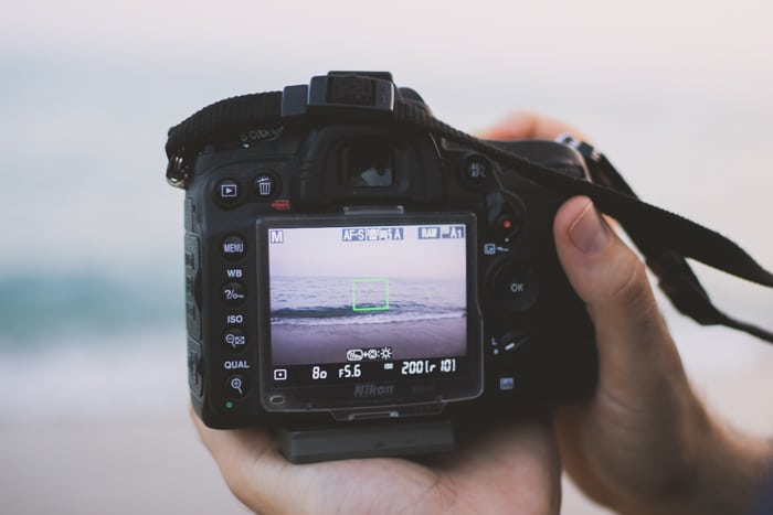 Cerca de una persona que toma una foto de un paisaje marino con una cámara DSLR