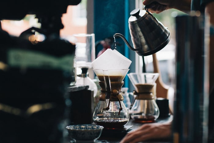 Un barista vertiendo café en un filtro v60 en una cafetería concurrida