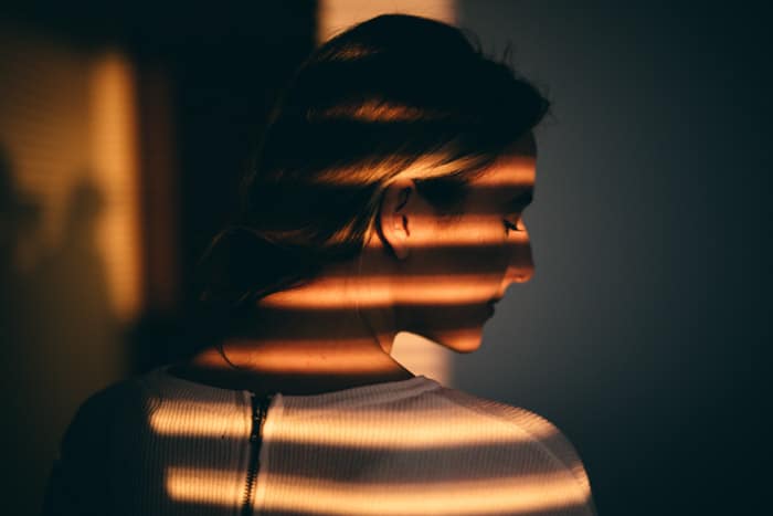 Moody claroscuro retrato ligero de una niña cubierta por sombras rayadas