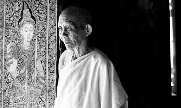 Un portarit en blanco y negro de un monje budista posando junto a la luz de la ventana