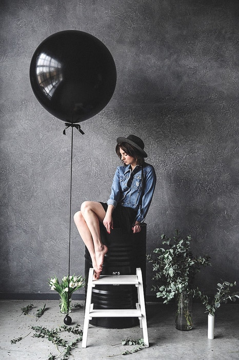 Una modelo femenina posando junto a un gran globo negro en un estudio de fotografía- pasantías de fotografía