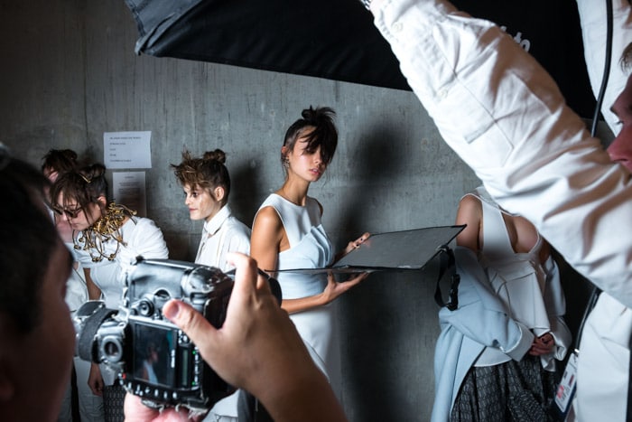 Un grupo de modelos y fotógrafos entre bastidores en una sesión de moda.