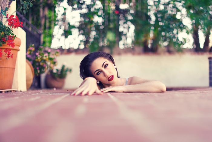 Una foto de retrato creativo de un modelo femenino que surge de las tablas del suelo de color rosa