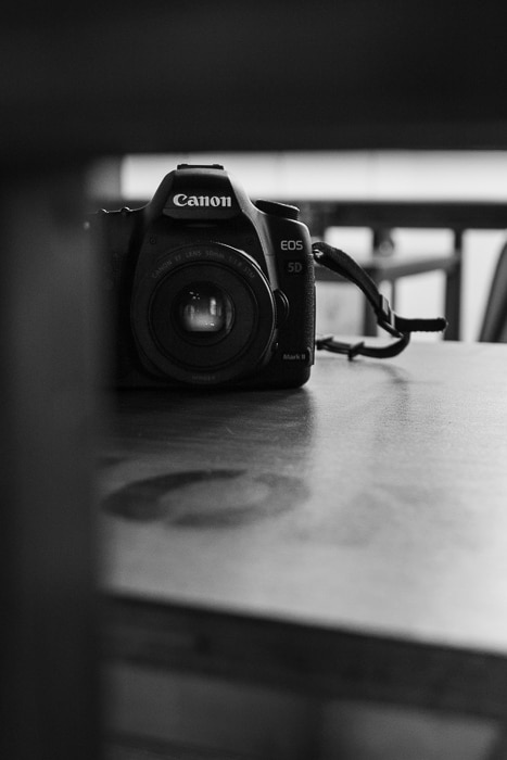 Fotografía en blanco y negro de una cámara réflex digital de Canon sobre una mesa.