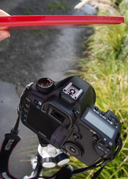 Foto de un trípode y una cámara con el fotógrafo usando un cuaderno como equipo de fotografía.