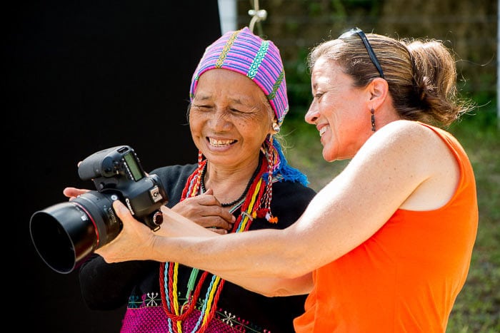 Dos mujeres riendo y revisando fotos con una cámara DSLR: cómo iniciar un club de fotografía