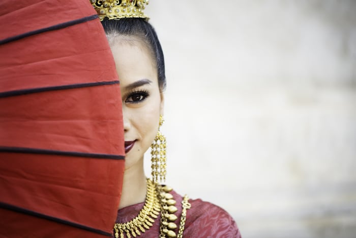 Interesante idea de composición de fotografía de una hermosa niña tailandesa con la mitad de la cara cubierta por un paraguas