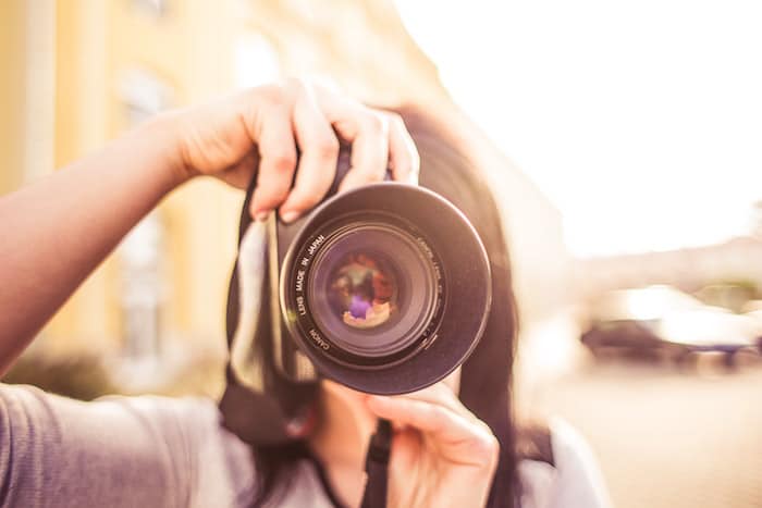 Una niña apuntando una cámara hacia el fotógrafo sobre un fondo borroso suave: consejos para el seguro de fotografía y cámara
