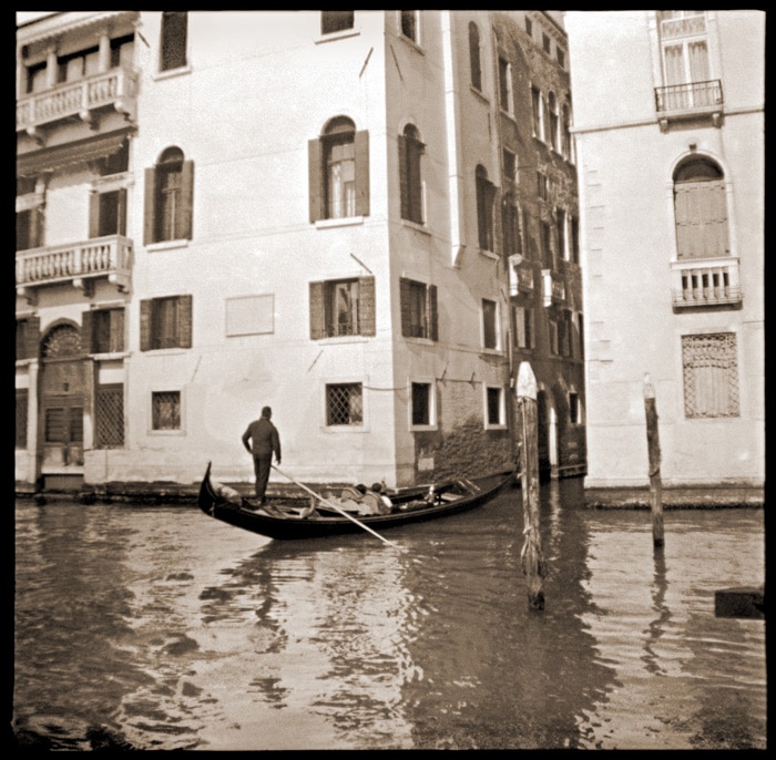 Una foto de caffenol en blanco y negro de un hombre en una góndola en Venecia.