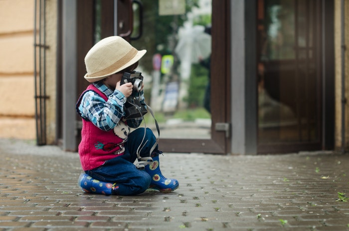 Foto de una niña tomando una foto en la calle