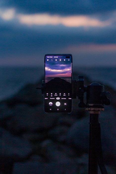 un teléfono inteligente en un trípode capturando una gloriosa puesta de sol