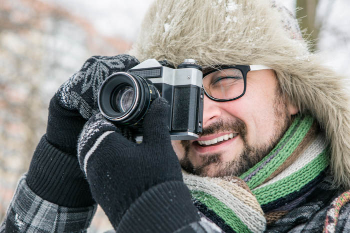 Chico tomando una foto en invierno mientras usa guantes de fotografía al aire libre