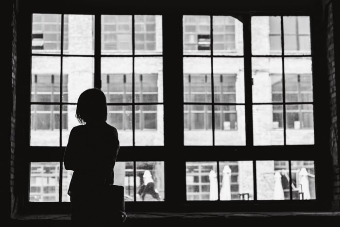 Una foto en blanco y negro de una niña mirando por una ventana