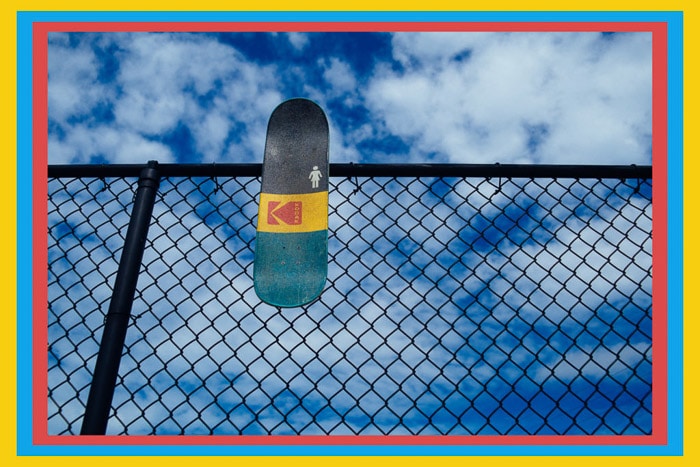 Una patineta apoyada en una valla de alambre con un borde de color - marcos de Photoshop