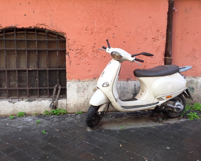 Una motocicleta Vespa en la esquina de una calle en Roma