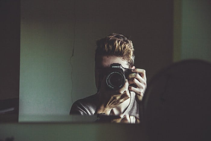 Un fotógrafo masculino hablando de un autorretrato de sí mismo a través del espejo - temas de fotografía