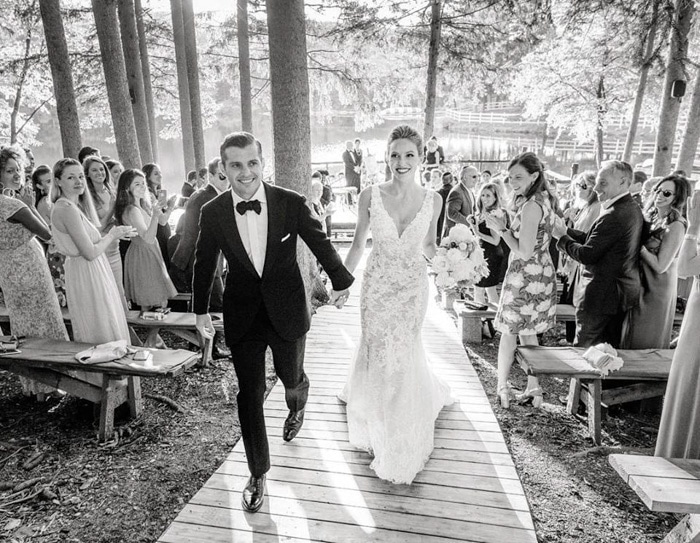 Retrato de boda en blanco y negro de la pareja caminando por el pasillo por Heather Waraksa