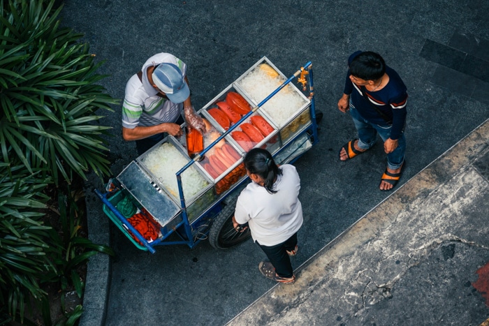 Una fotografía callejera de un vendedor de comida sirve comida de su carrito