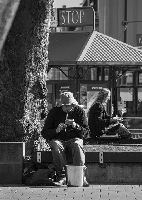 Retrato callejero en blanco y negro de un hombre tocando una flauta al aire libre en un día soleado