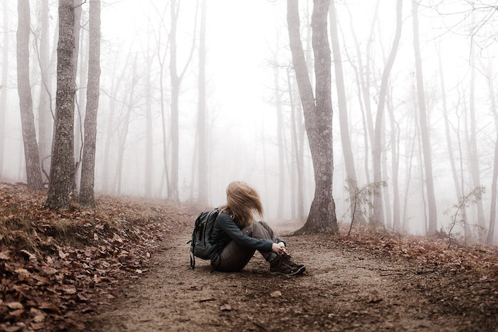 Retrato atmosférico de una niña sentada en un bosque editado con la función de desvanecimiento de Lightroom