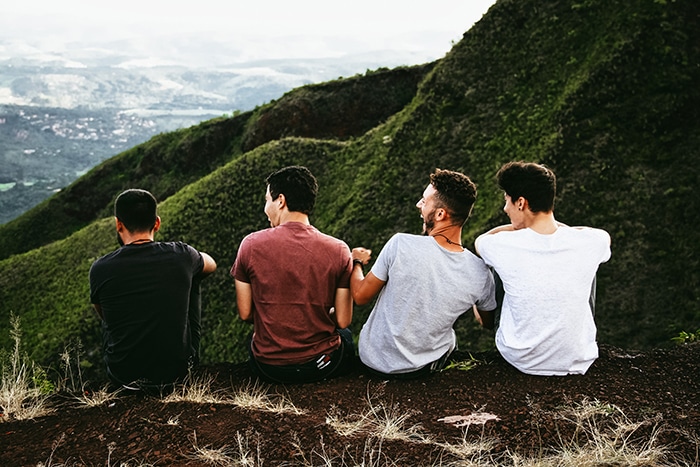 Cuatro amigos sentados entre un hermoso paisaje montañoso - retratos de estilo de vida