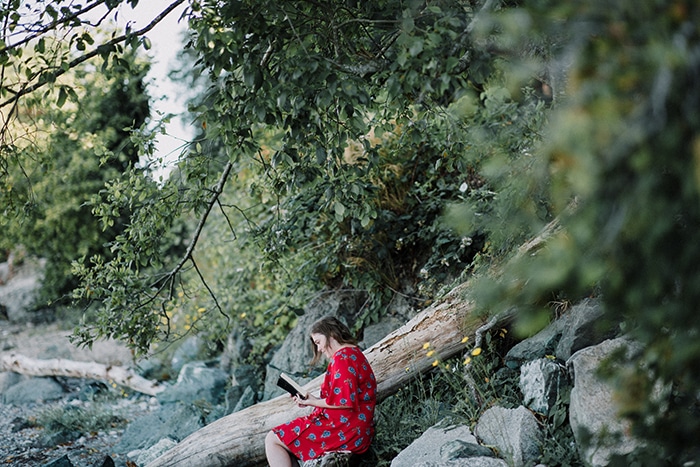 Una modelo femenina leyendo un libro debajo de un árbol - retratos de estilo de vida
