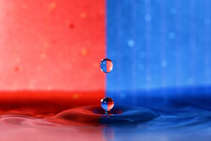 Un fondo rojo y azul con una salpicadura de fotografía de gota de agua en primer plano