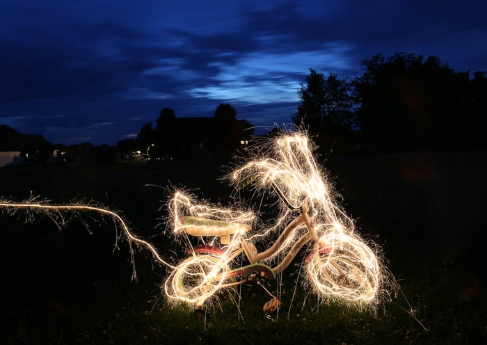 Una bicicleta rodeada de pintura con luz, al aire libre por la noche, filmada con herramientas de pintura con luz LED