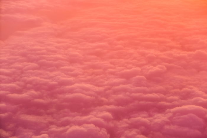 Una foto de color rosa y naranja de un cielo nublado tomada desde arriba