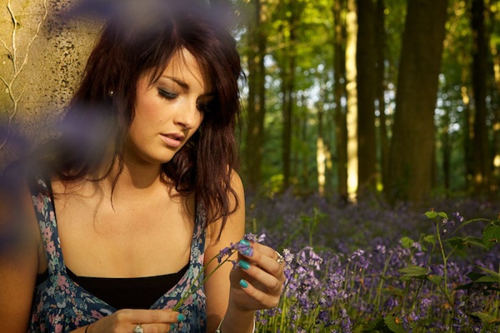 Un retrato al aire libre de un modelo femenino con flores de color púrpura