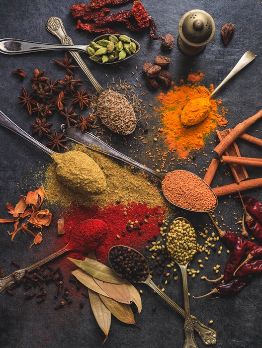 Fotografía de comida india con cucharas y especias esparcidas sobre una mesa