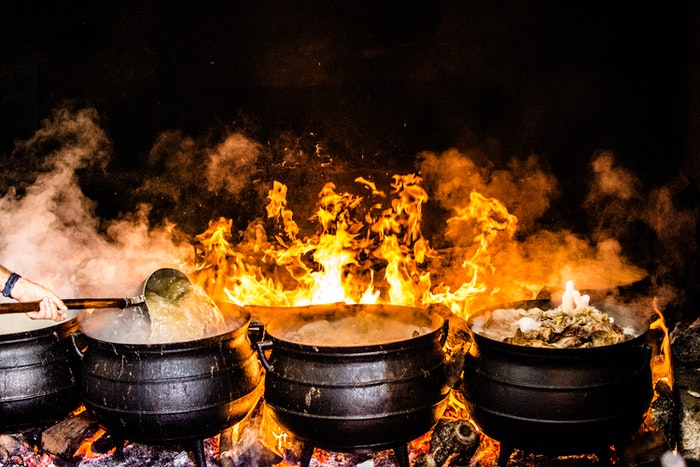 Escena de comida india que se cocina en ollas sobre un fuego abierto