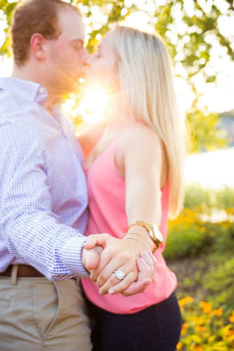 fotografía de compromiso de una pareja besándose, con la atención puesta en el anillo - la foto fue tomada usando reflectores para la iluminación