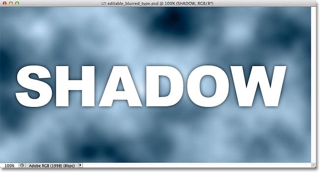 La sombra paralela aparece alrededor de los bordes de las letras en la ventana del documento.  Imagen © 2012 Photoshop Essentials.com.